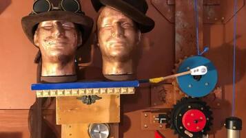 Two head sculptures mounted on a wooden structure with gears and a pulley system.