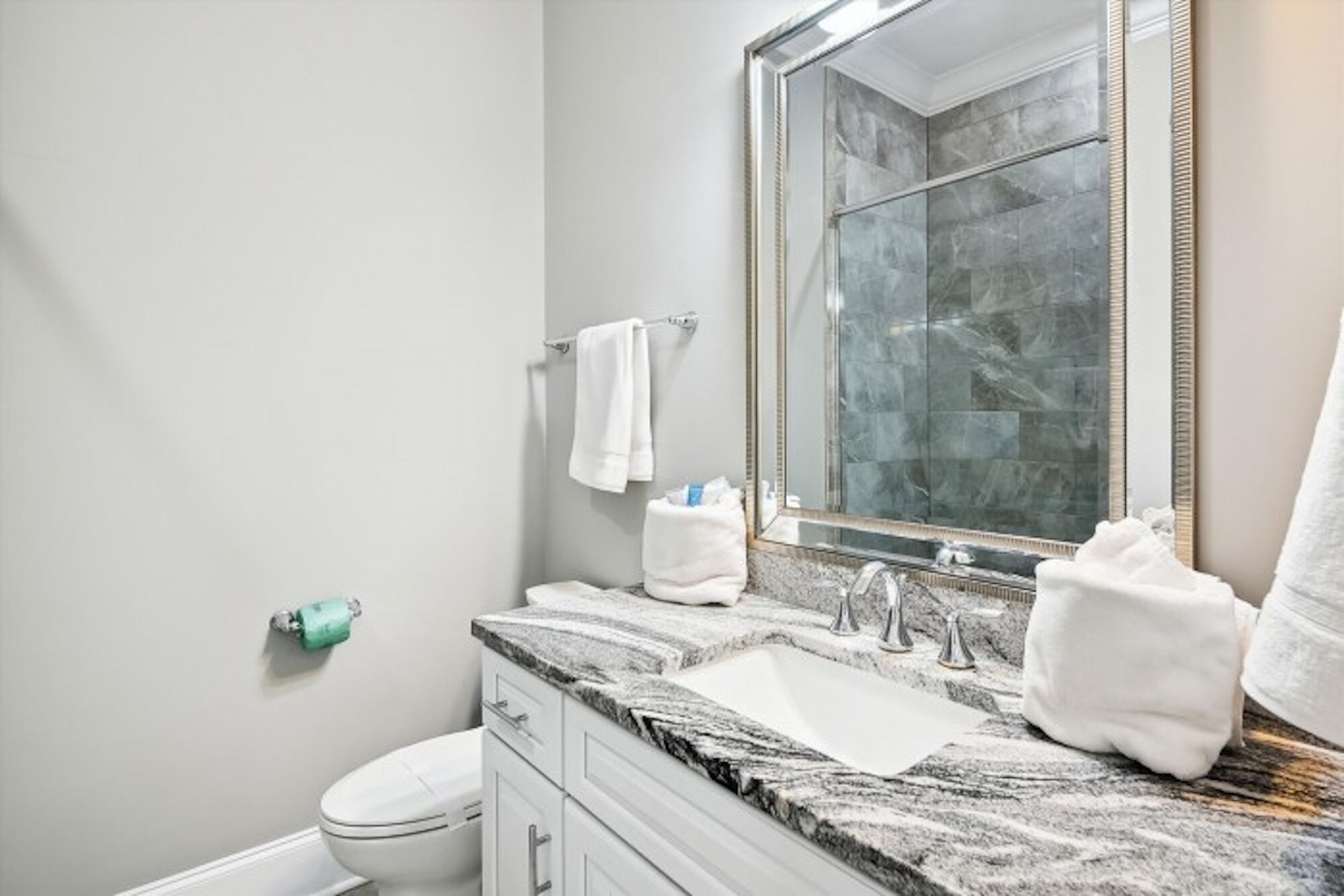 A modern bathroom with a marble sink, a large mirror, and a toilet.
