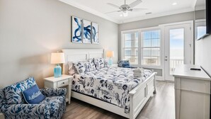 A bedroom with a bed, a nightstand, a chair, a desk, and a ceiling fan.