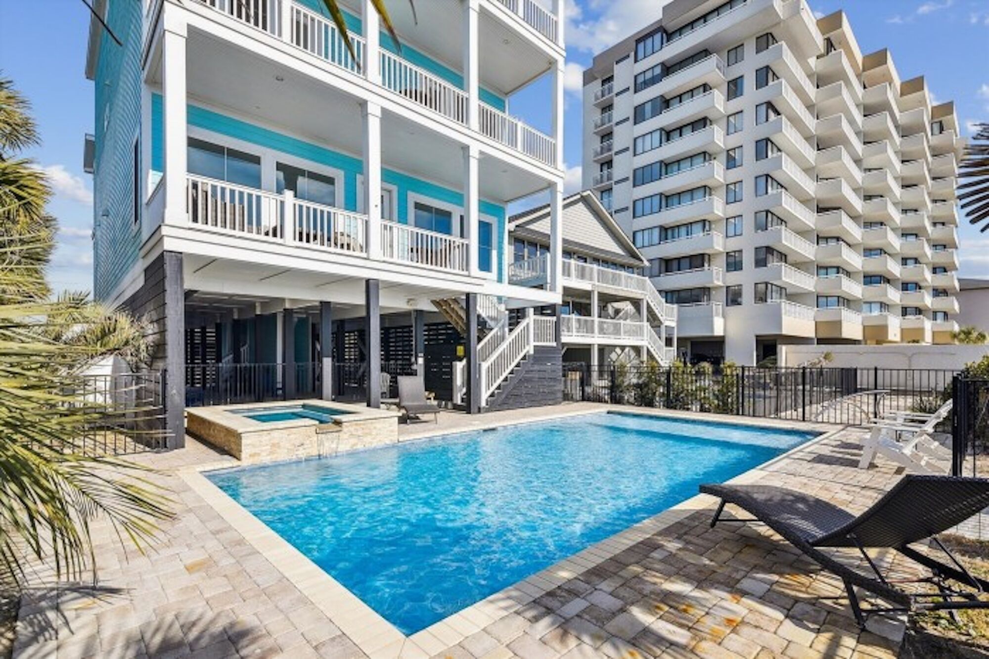 Un hotel moderno con piscina, varios balcones y vistas a un edificio alto.