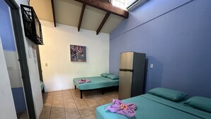 A room with two single beds, a kitchenette with a refrigerator, and a small bathroom. - Wide Mouth Frog Conchal (Cabo Velas)
