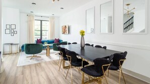 Un espace de repas moderne avec une longue table, des chaises noires et un canapé vert.