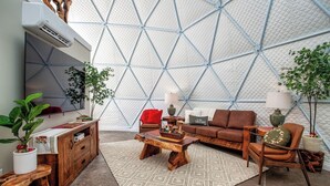 A modern living room with a geometric patterned wall, a wooden coffee table, a brown sofa, and a TV mounted on the wall. - Traverse City - Luxury on the Edge -13 (Williamsburg)