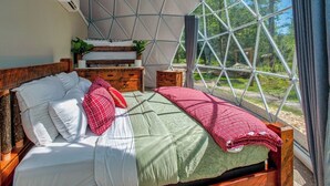 A bedroom with a large window, a wooden bed, and a small bedside table. - Traverse City - Luxury on the Edge -13 (Williamsburg)