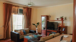 A living room with a sofa, coffee table, TV stand, and a dining area with a table and chairs. - A peaceful, relaxing place with privileged view of the sea. (Tabua)