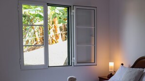 A bedroom with a bed, a window, a nightstand, and a lamp. - A peaceful, relaxing place with privileged view of the sea. (Tabua)