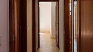 A hallway with wooden doors and a tiled floor leading to a room. - A peaceful, relaxing place with privileged view of the sea. (Tabua)