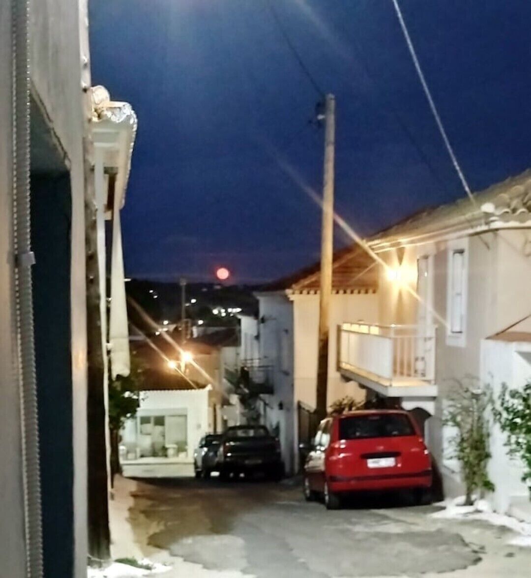 A narrow street with parked cars and buildings on both sides.