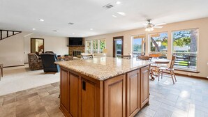 A spacious kitchen with a large island, a dining area with chairs, and a TV mounted on the wall.