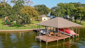 A docked boat with a covered seating area, a small deck, and a lifebuoy.