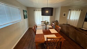 A dining area with a wooden table, chairs, a vase with flowers, and a hanging light fixture. - 15-min Walk to Stadium w/ Huge Yard + Firepit (Arlington)