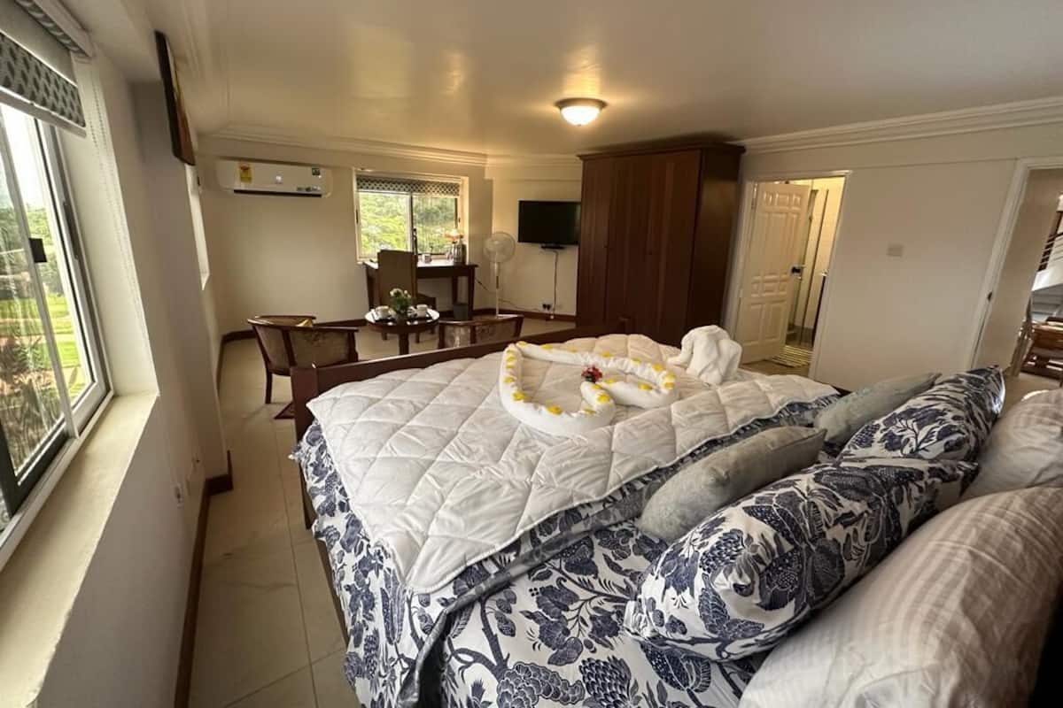 A bedroom with a bed, a desk, a chair, and a TV.