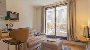 Una camera d'albergo con un letto, una scrivania con un bollitore, una sedia e una finestra con tende.