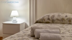 A neatly made bed with a patterned bedspread and two folded white towels on the side. - ClickSardegna Casa Carlo Alberto In the Heart of Catalan Alghero near the beach (Alghero)