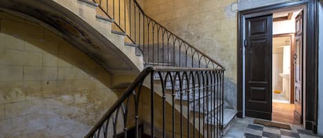 A staircase with a checkered floor and a dark door at the bottom.