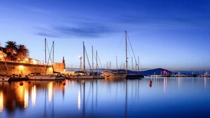 A marina with multiple sailboats docked, calm water reflecting the boats, and a stone wall with a building on the left. - ClickSardegna Casa Carlo Alberto In the Heart of Catalan Alghero near the beach (Alghero)
