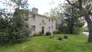 A two-story house with a front porch, a chimney, and a well-maintained lawn. - 2828 Main Street (Barnstable)