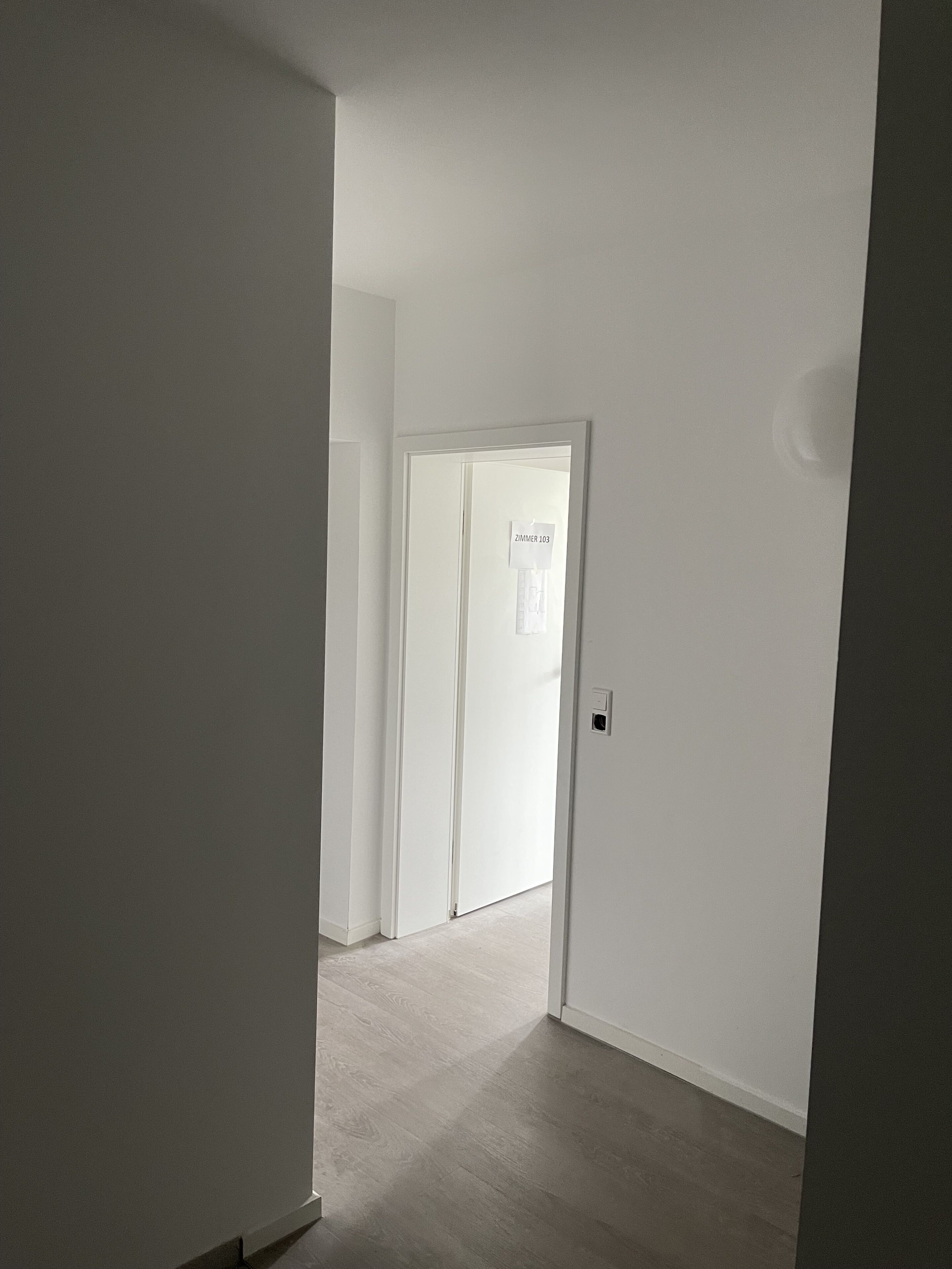 A hallway with a door labeled "Zimmer 103" leading to a room.