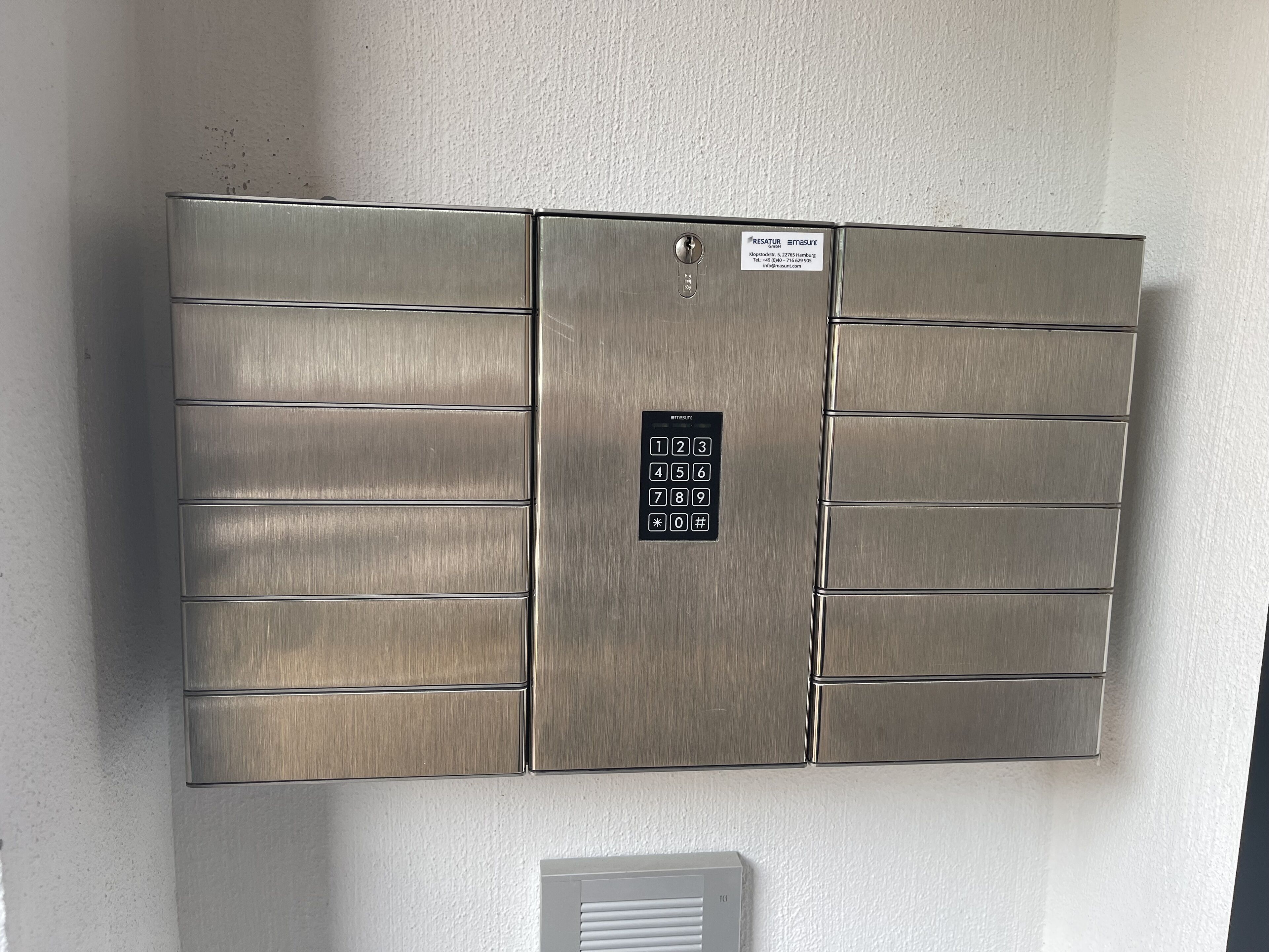 Een metalen, wandcontactdoos met numeriek toetsenbord en een slot.