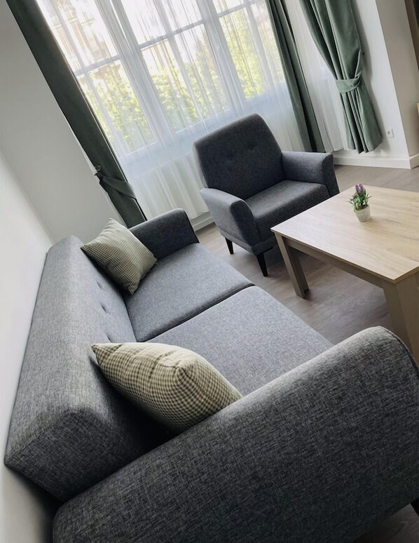Una sala de estar moderna con un sofá gris, un sillón a juego y una mesa de centro de madera.