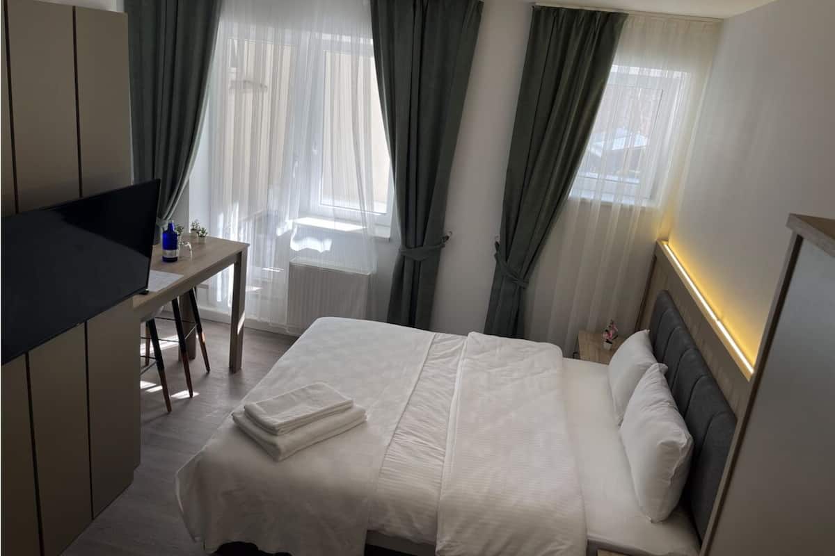 A hotel room with a bed, a desk, and a TV.