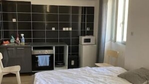 A bedroom with a bed, a desk, a chair, and a kitchenette. - T1 Vieux Port Opera (Marseille)