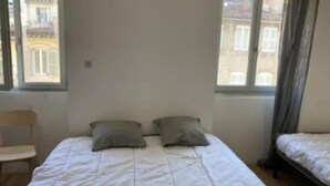 A simple room with a bed, two pillows, a chair, and a window. - T1 Vieux Port Opera (Marseille)