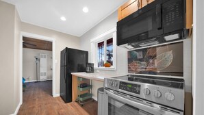 Una cocina moderna con electrodomésticos de acero inoxidable, un armario de madera y una ventana con un diseño de hojas decorativas.