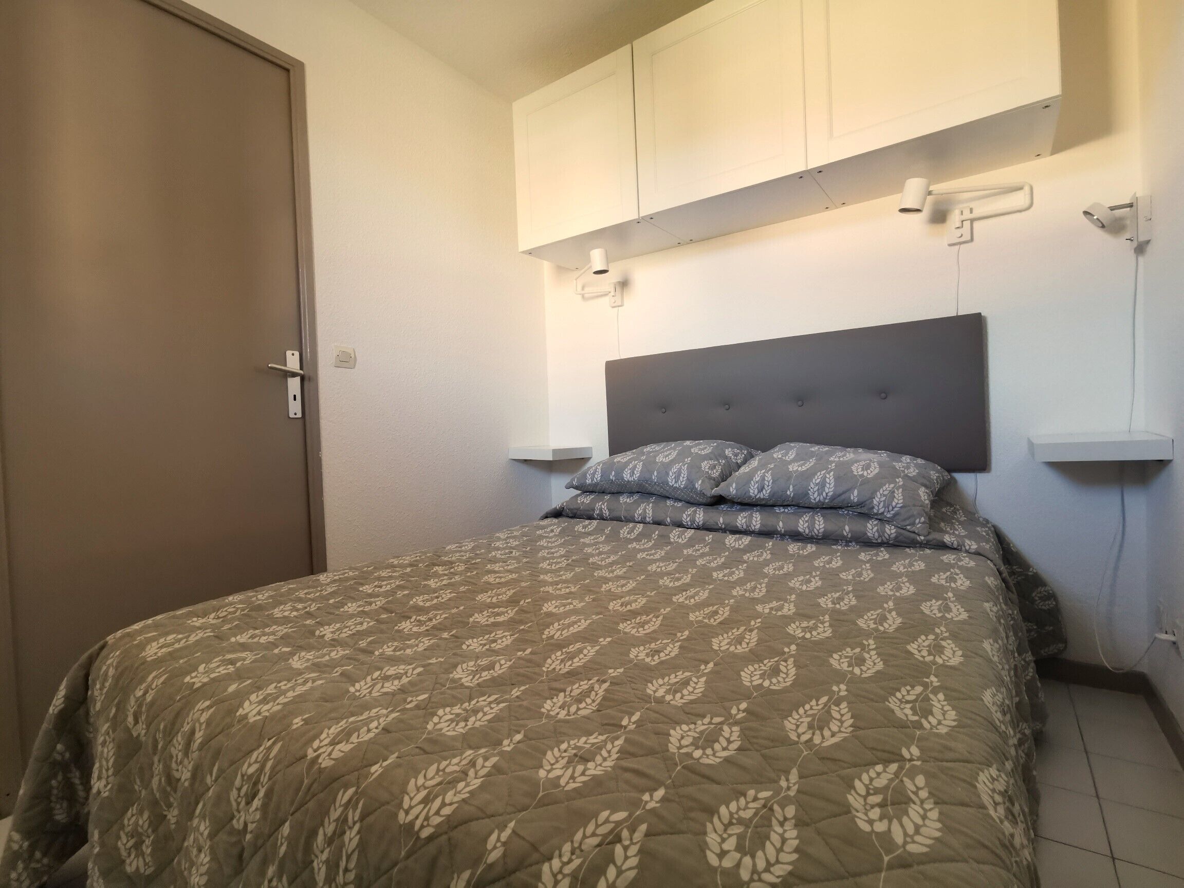 A bedroom with a bed, a wardrobe, and a nightstand.