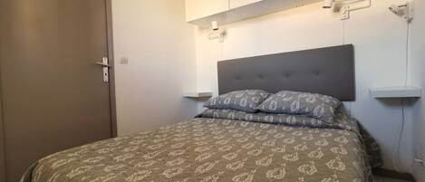 A bedroom with a bed, a wardrobe, and a nightstand.
