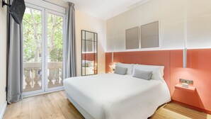 A bedroom with a large bed, a sliding glass door to a balcony, and a wall-mounted TV. - LeMar by Aspasios (Barcelona)