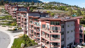 A multi-story residential building with balconies, large windows, and a landscaped garden area.