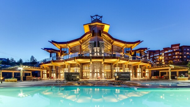 A multi-story building with a pool in front.