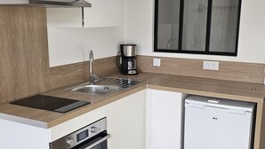 A compact kitchen with a stove, oven, sink, and a coffee maker.