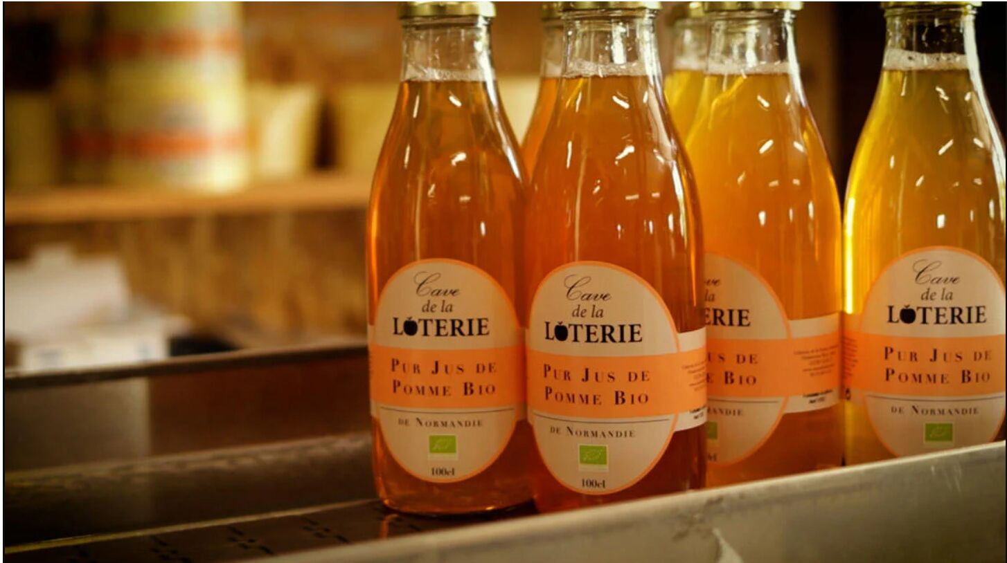 Bottles of 'Cave de la Loterie' cider on a shelf.
