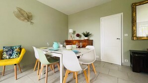 Un comedor con una mesa blanca dispuesta para cuatro personas, rodeado de sillas con patas de madera.