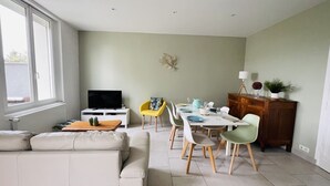 Una sala moderna con un sofá, una mesa de comedor con sillas, un televisor y un mueble aparador.