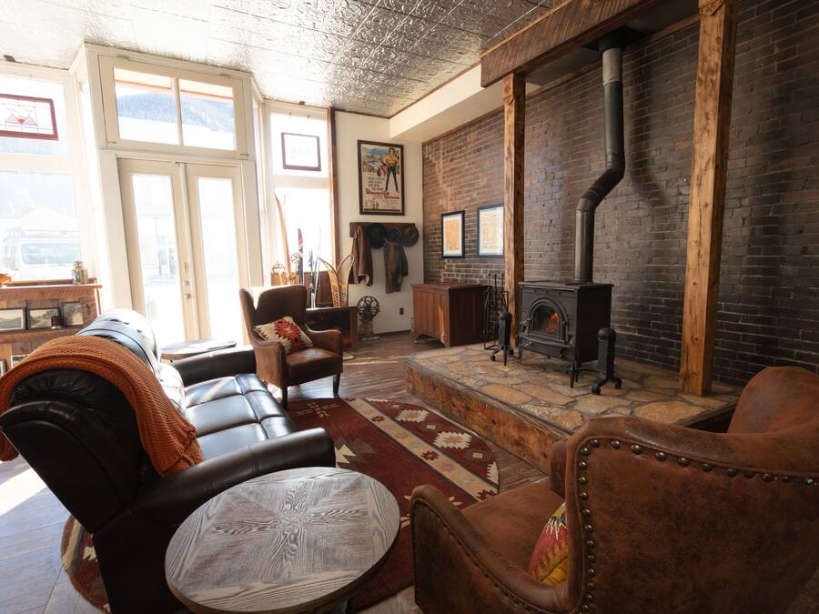 A cozy living room with leather sofas, a fireplace, and a stone fireplace surround.