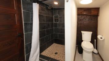 Un baño con ducha, inodoro y puerta de madera.