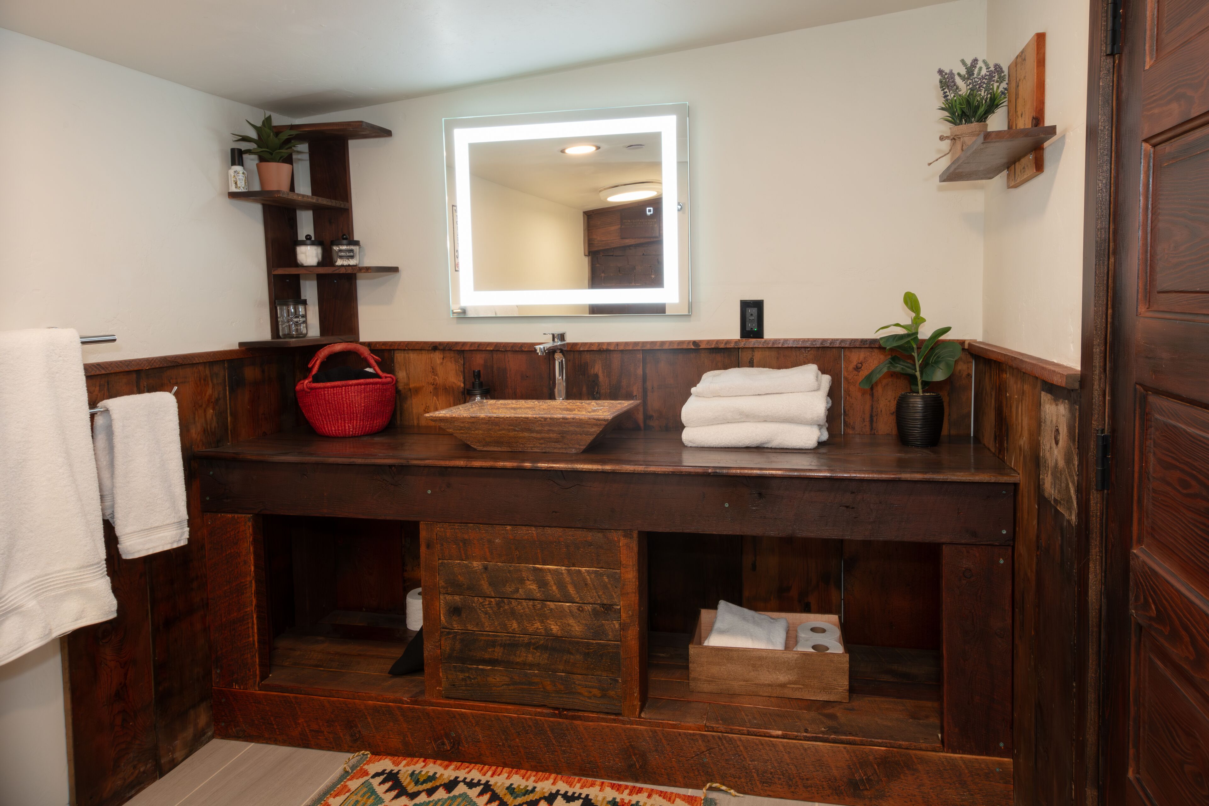 Ein Badezimmer mit einem Holzbadezimmerschrank, einem großen Spiegel und einem Handtuchhalter.