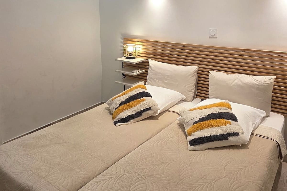 Une chambre d’hôtel moderne avec un grand lit, une table de chevet avec une lampe et un luminaire au plafond.
