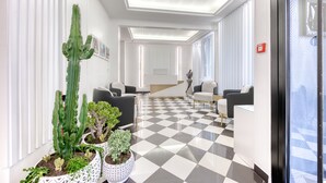 En moderne lobby med skakterningsgulv, sorte og hvide sofaer og plantekasser.