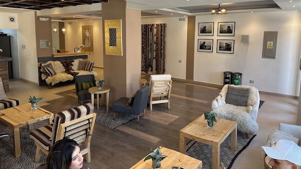 Un vaste espace de vie doté d’un plafond haut, de poutres en bois et d’un assortiment de différents types de sièges, notamment des canapés et des fauteuils.