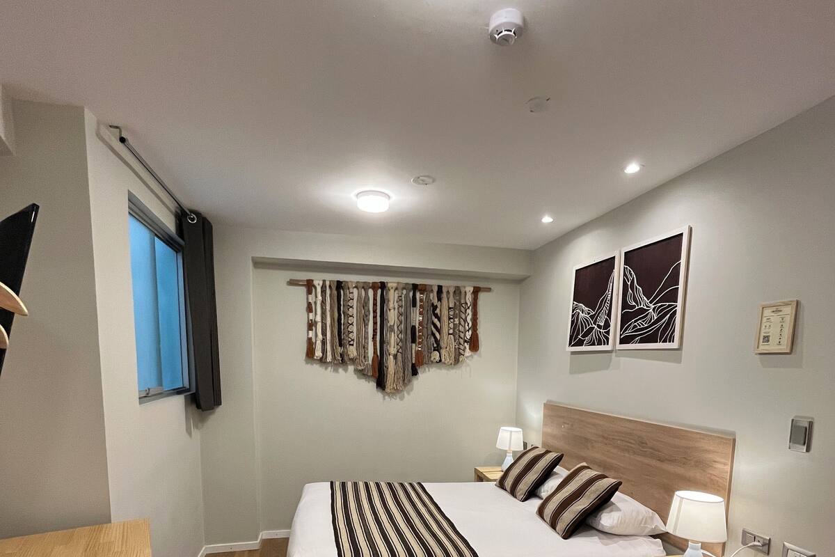 Una habitación de hotel moderna con una cama grande, mesitas de noche, un escritorio y obras de arte en las paredes.