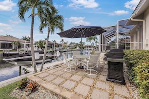 Une terrasse avec une table et des chaises, un barbecue et une vue sur une marina remplie de bateaux.