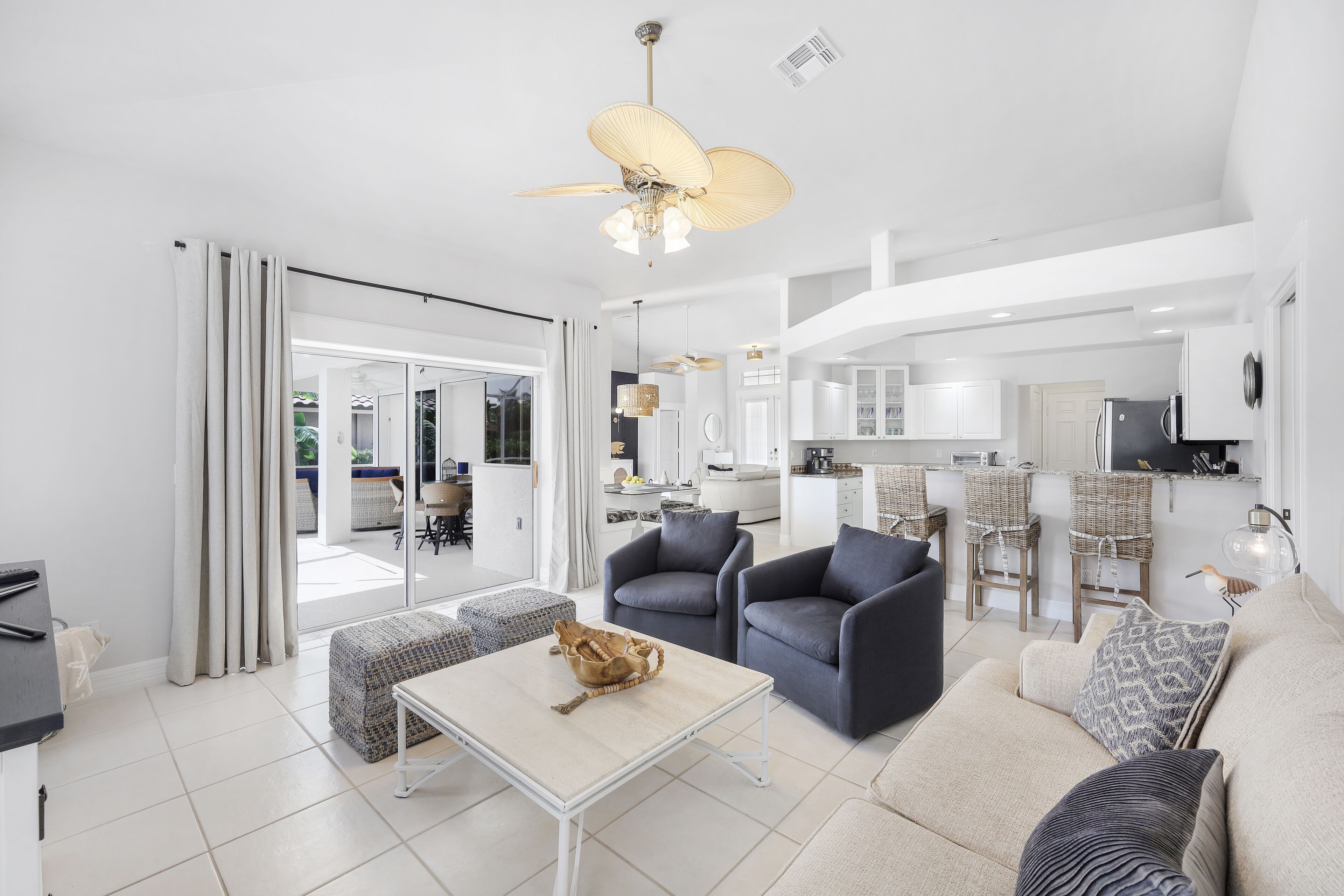 A spacious living area with a sofa, armchairs, a coffee table, and a dining area with bar stools.