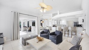 A spacious living area with a sofa, armchairs, a coffee table, and a dining area with bar stools.