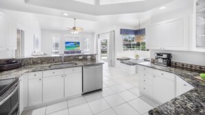 A modern kitchen with white cabinets, granite countertops, and a dishwasher.