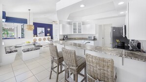 A modern kitchen with a central island, bar stools, and a built-in refrigerator.