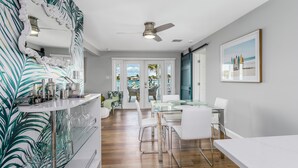 A modern kitchen with a white countertop, glass shelving, and a view of the pool area.